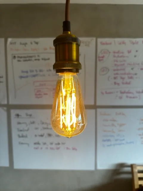 Vintage-style light bulb in front of whiteboard sheets with handwritten feature sketches